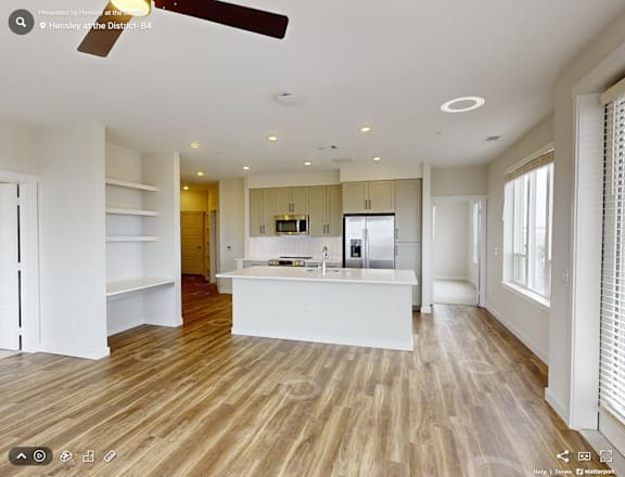 A spacious kitchen with wooden flooring and white walls.