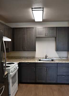 A kitchen with dark wood cabinets and a white stove top oven.