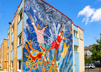 A mural of two people dancing is painted on the side of a building.