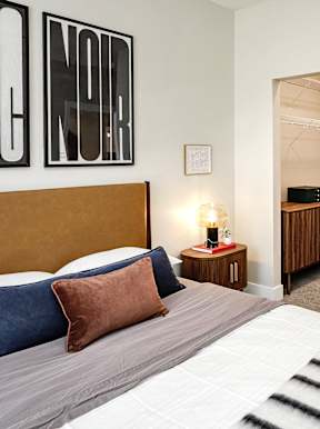 A bedroom with a bed, pillows, and a nightstand with a lamp.
