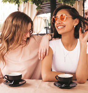 Two women sitting at a table with cups of coffee.