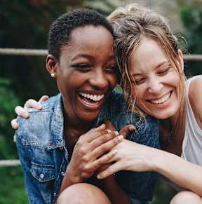 Two women laughing and hugging each other.