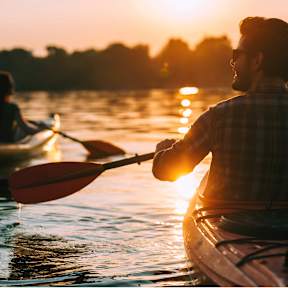 Two people kayaking on a body of water during sunset.