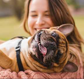 A woman is holding a happy dog in her arms.