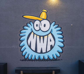 a mural of a monster with a yellow hat on a blue wall
