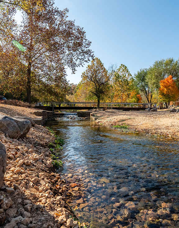 A stream flows through a rocky landscape with trees in autumn colors.