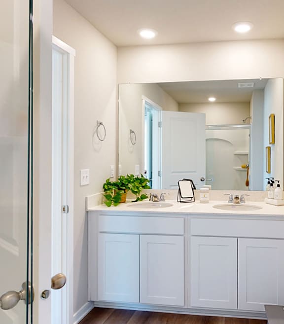 A white bathroom with a double sink and a mirror.