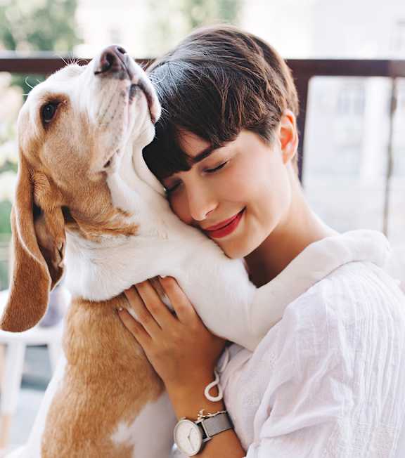 A woman is hugging a dog on a balcony.