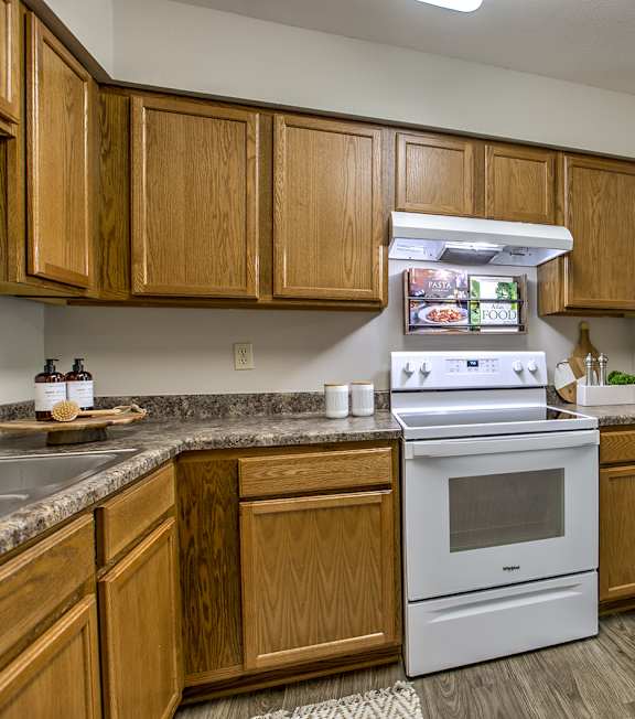 A kitchen with wooden cabinets and a white stove top oven.