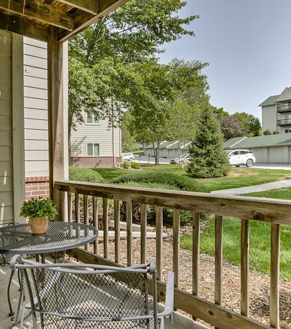 A patio with a table and chairs overlooking a grassy area.