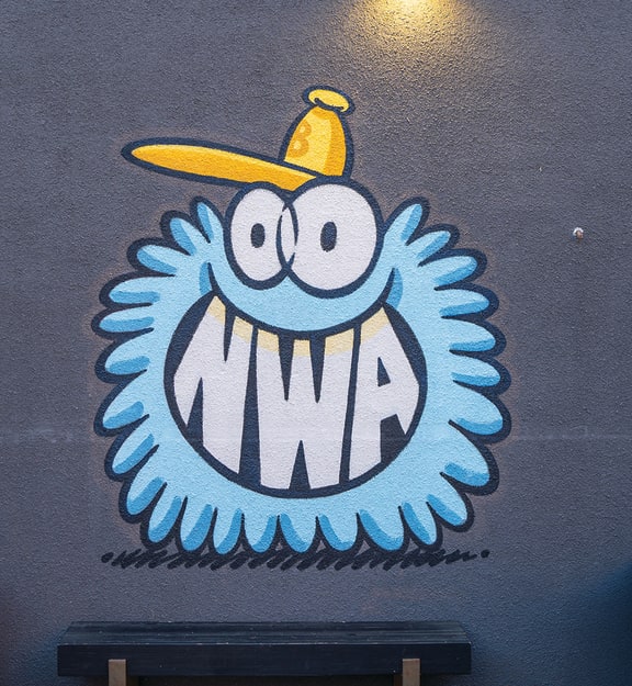a mural of a monster with a yellow hat on a blue wall