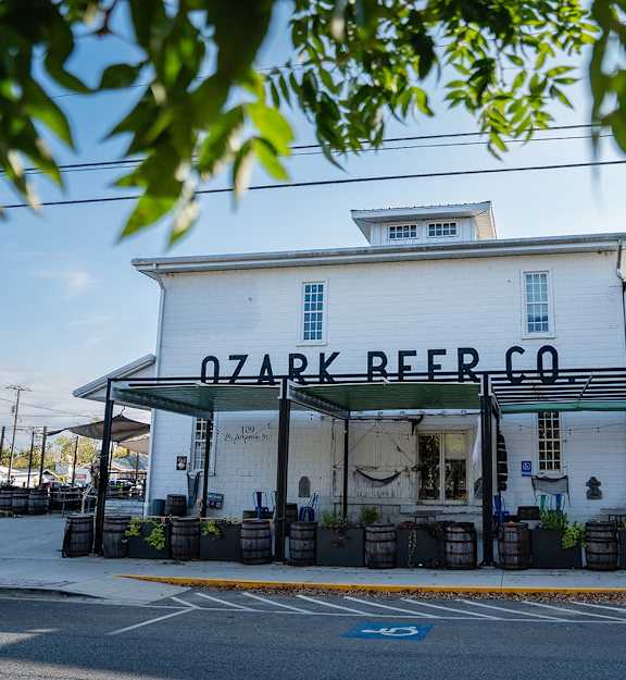 A white building with a black awning that says Ozark Beer Co.