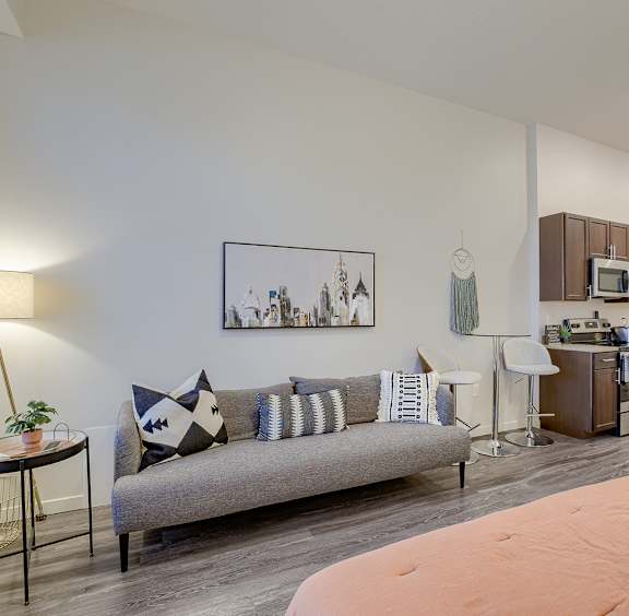 A living room with a grey sofa and a painting on the wall.