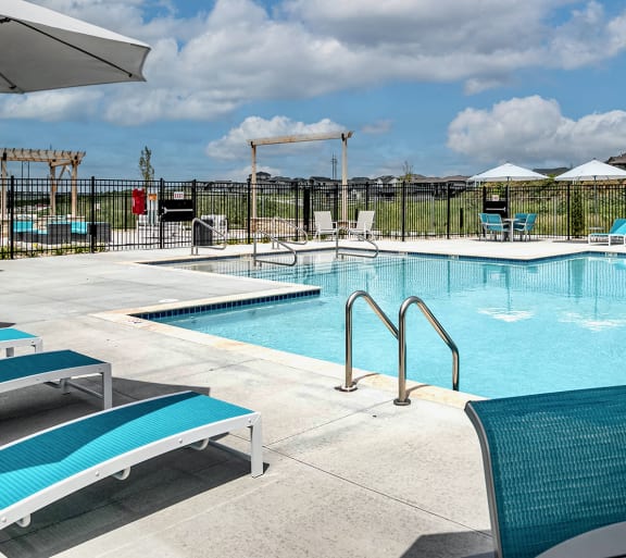 a resort style pool with lounge chairs and umbrellas