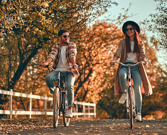 Two people riding bicycles in a park.