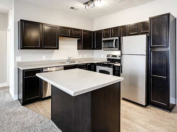 A kitchen with black cabinets and a white island.
