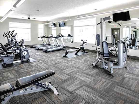 a gym with cardio equipment and weights on a wooden floor