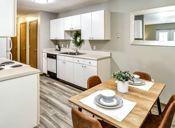 a kitchen with white cabinetry and a white stove top oven next to a wooden table with