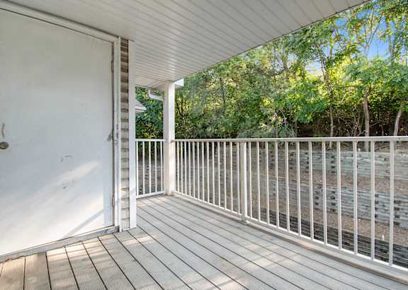 A white door is open to a deck with a white railing.