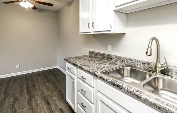a kitchen with white cabinets and a stainless steel sink