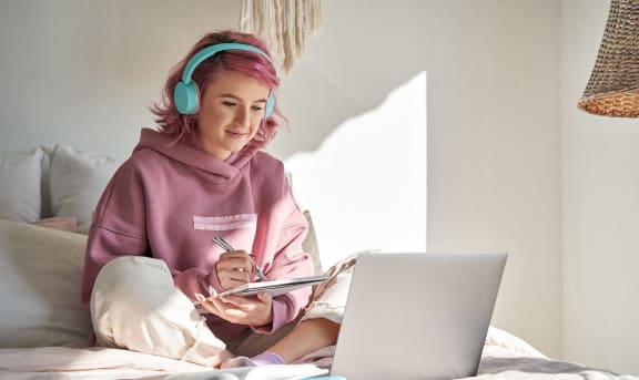 a woman sitting on a bed with a laptop computer and headphones on