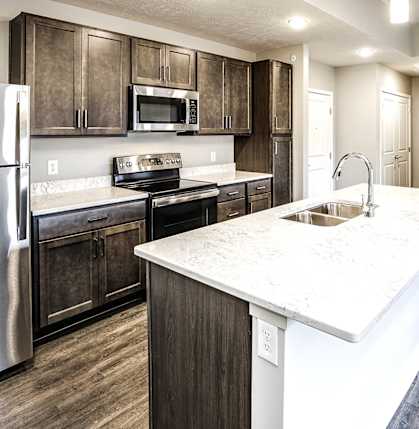 A kitchen with a white counter top and a stainless steel refrigerator.