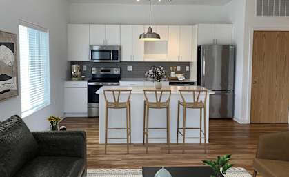A kitchen with a black sofa and a bar stool.