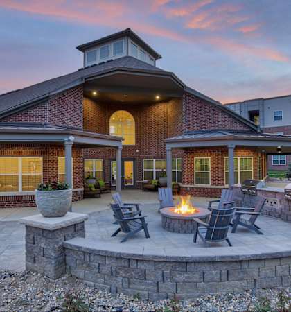 a patio with a fire pit and chairs in front of a building