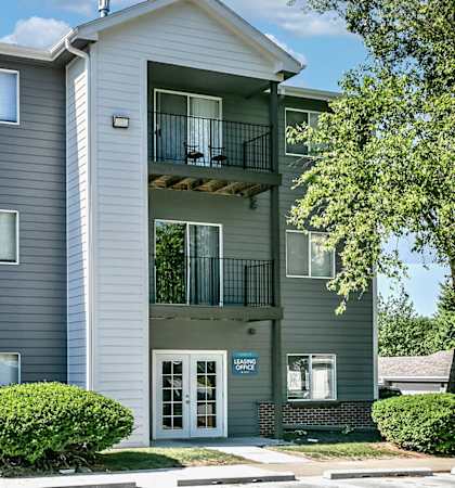 a grey apartment building with a balcony and a front door