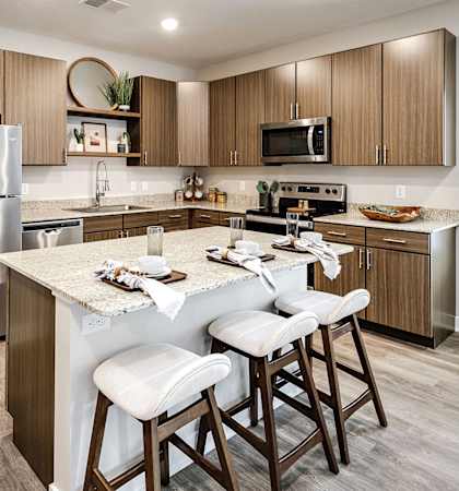 spacious kitchen with stainless steel appliances and a large island with 3 bar stools