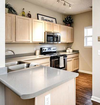 A kitchen with a stove top oven and a microwave at Autumn Grove Apartments, Omaha