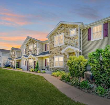 a row of homes on a sidewalk with a sunset in the background