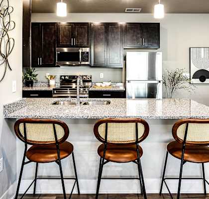 a kitchen with a marble counter top with three stools