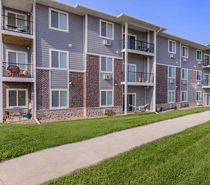 Apartment building with balconies and a lawn in front.