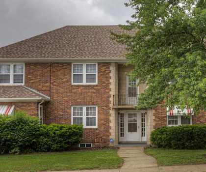 A brick house with a tree in front.