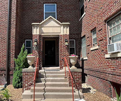 A red brick building with a black door and a small window above it.