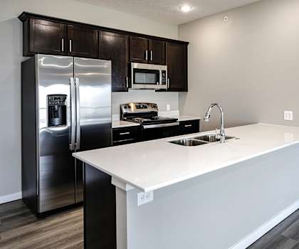 a kitchen with a white counter top and a stainless steel refrigerator
