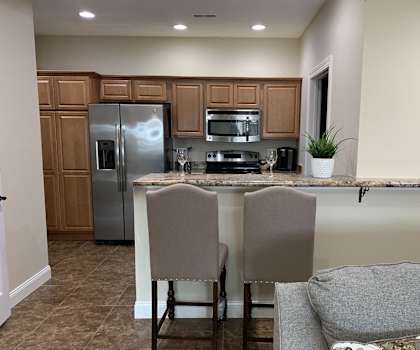 A kitchen with a refrigerator, microwave, oven, and sink.
