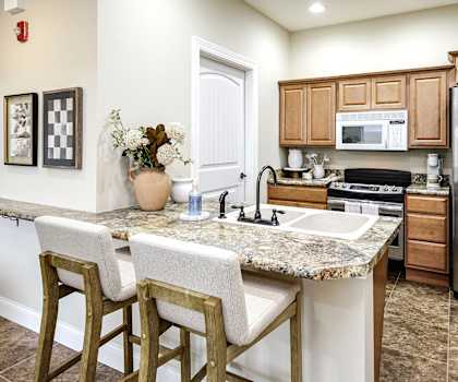 A kitchen with a marble countertop and wooden bar stools.
