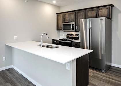 a kitchen with a white counter top and a stainless steel refrigerator