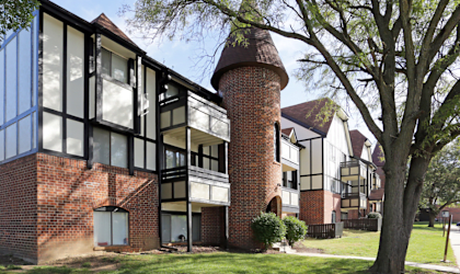 a red brick apartment building with a large tree in front of it