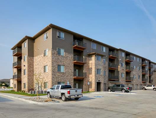 A large apartment building with a parking lot in front.