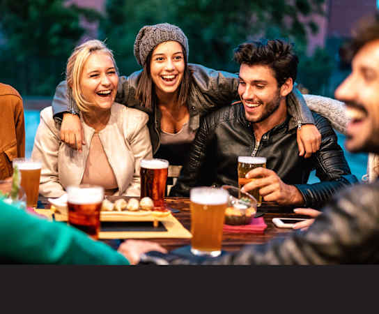a group of people sitting around a table with beers