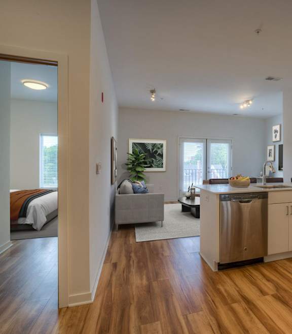 A kitchen with a white counter and wooden floors.