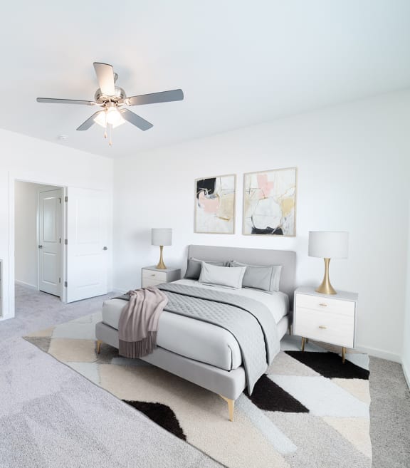a white bedroom with a bed and a ceiling fan