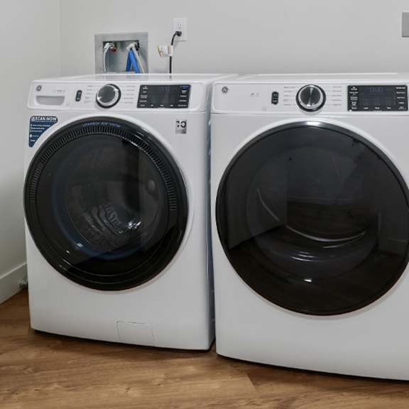 Two white front load washing machines in a laundry room.