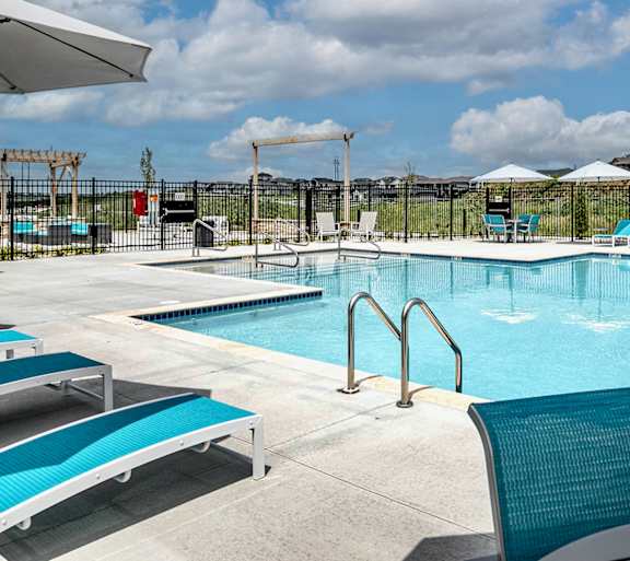 a resort style pool with lounge chairs and umbrellas