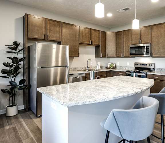 A kitchen with a marble countertop and wooden cabinets.
