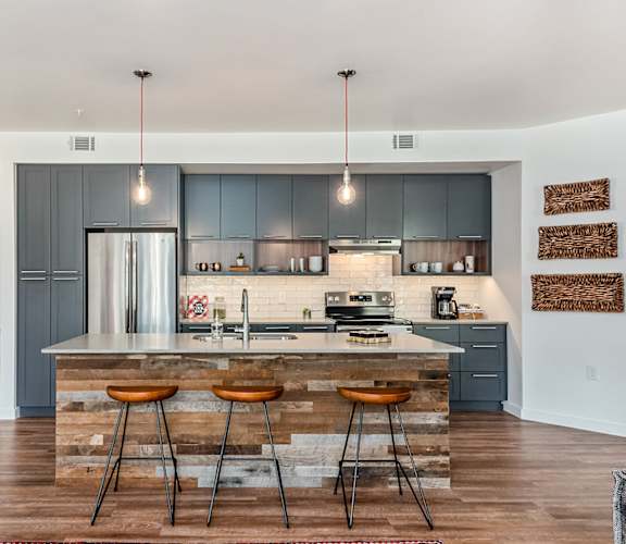 a kitchen with gray cabinets and a large island with three stools
