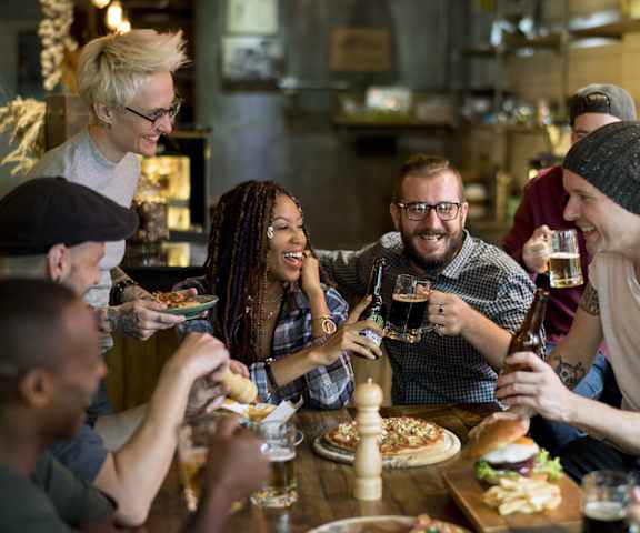 A group of people are gathered around a table eating and drinking.